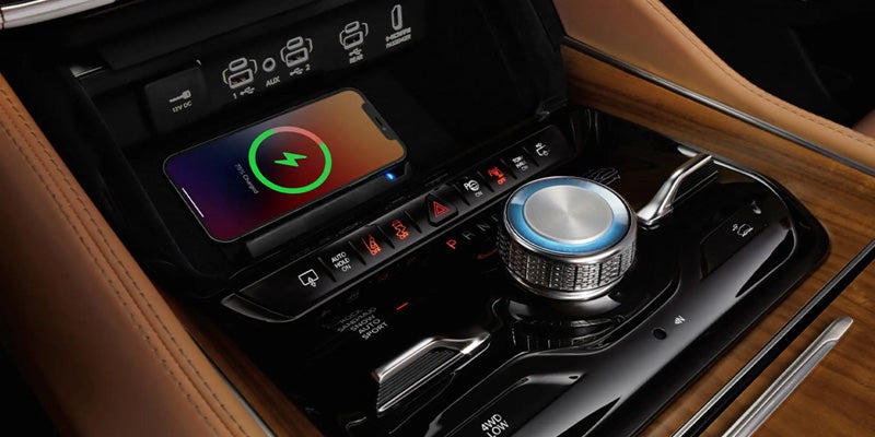 Jeep Wagoneer center console with a wireless charging pad, rotary control dial, and premium wood trim accents