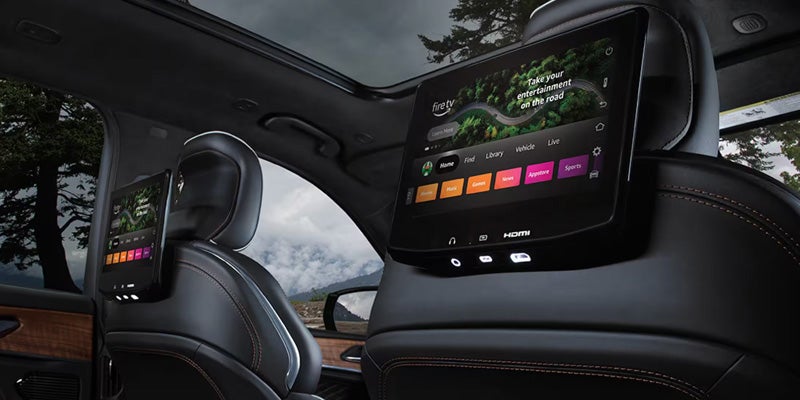 Jeep Grand Wagoneer rear cabin featuring seatback-mounted entertainment screens and premium passenger amenities