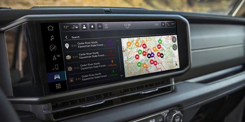 Vehicle infotainment touchscreen displaying an off-road navigation map with trail markers