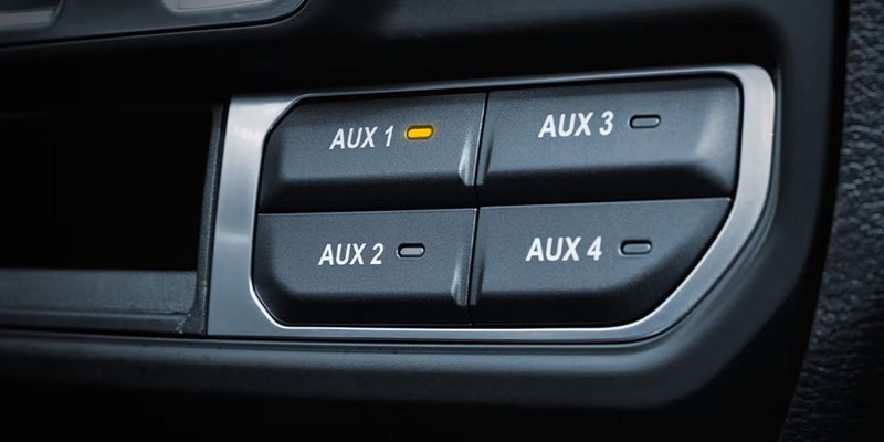 Close-up of Jeep Wrangler auxiliary control switches labeled AUX 1, AUX 2, AUX 3, and AUX 4 on the dashboard