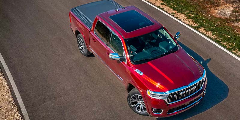 Overhead view of a shiny red Ram pickup truck on an asphalt road with a tan shoulder.