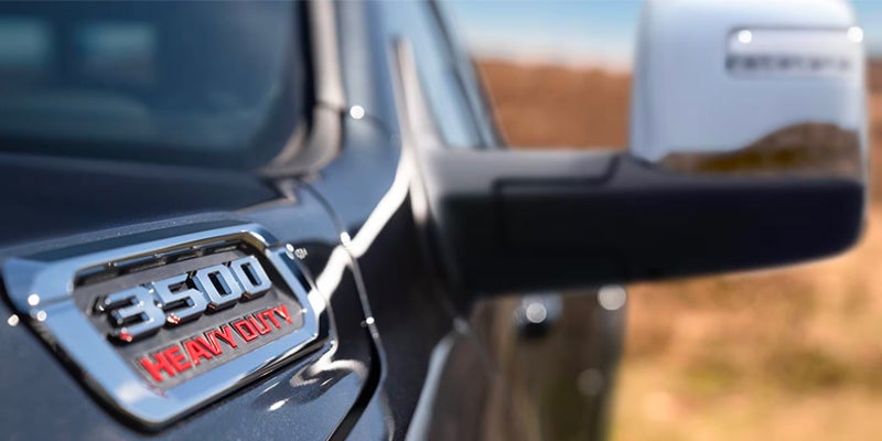 Close-up of a dark grey pickup truck's fender with a chrome "3500 HEAVY DUTY" emblem in red text.