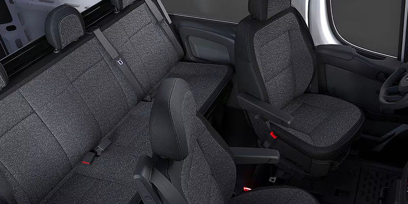 Interior view of a vehicle showing dark gray fabric seats with black trim, including a 3-person rear bench seat and two front seats with armrests.