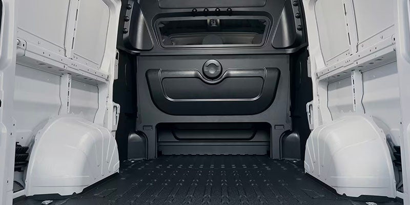 Interior view of an empty white cargo van's rear storage area, with a dark gray partition separating the cab.