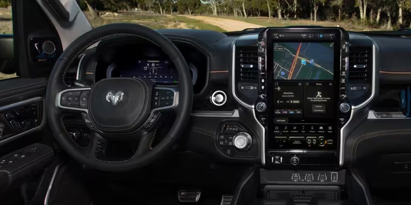 Interior of a modern vehicle showing the steering wheel and large touchscreen with navigation on the dashboard.