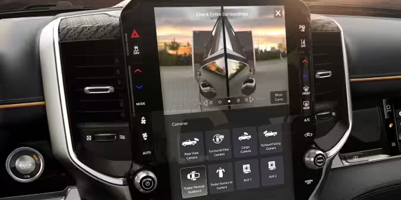 Car's infotainment screen showing a boat being towed, with camera options for rear view, surround, cargo, and trailer.