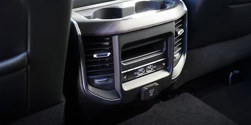 Rear car console with cupholders, air vents, USB ports, and a 115V AC outlet.